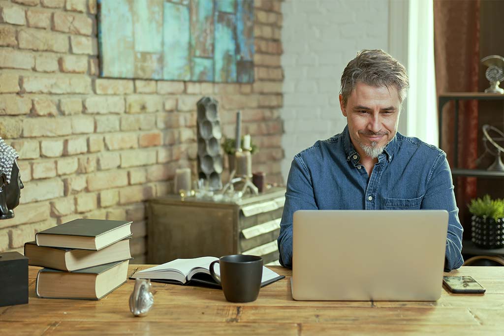 A man working at a laptop, sitting at a desk