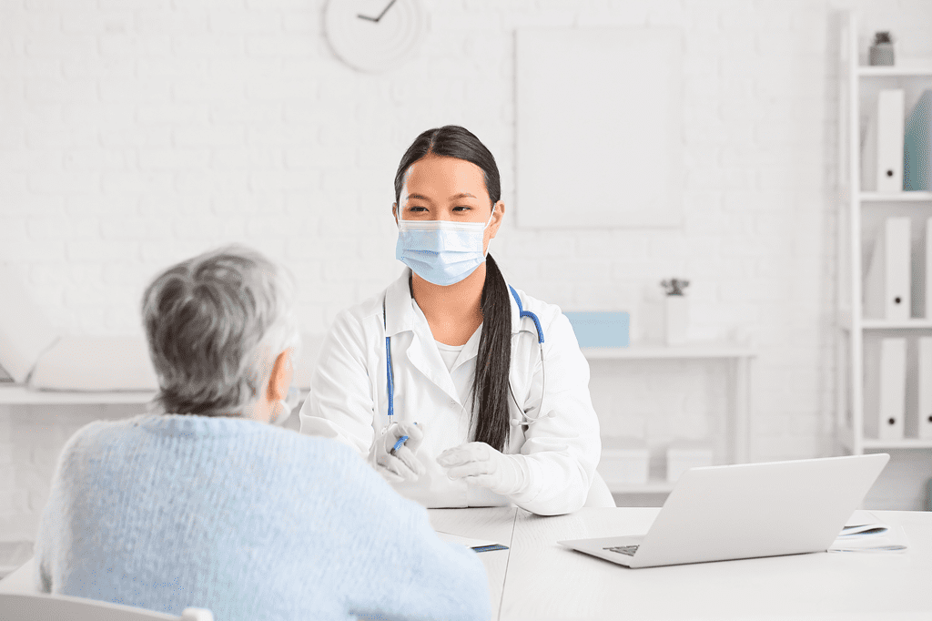 Doctor wearing a mask, talking with an older person.